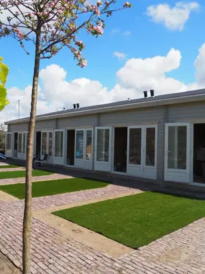 a building with a tree in front of it at Polderlodge in Hillegom