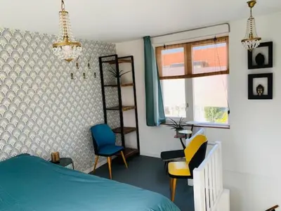a bedroom with a bed and chairs and a window at King almost by the sea in Zandvoort