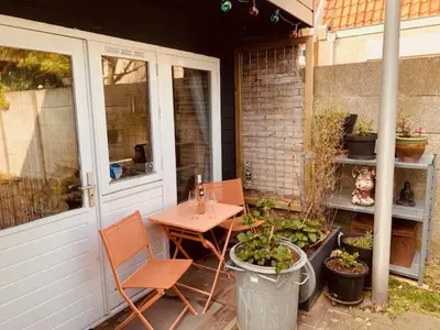 a patio with a table and chairs on a porch at King almost by the sea in Zandvoort