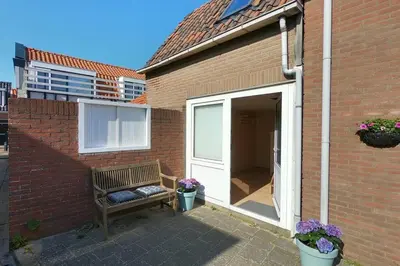 a bench sitting next to a brick building at Zomerhuis At Sea op top locatie in Egmond aan zee in Egmond aan Zee