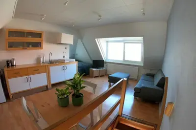 a kitchen and a living room with a table and a couch at Zomerhuis At Sea op top locatie in Egmond aan zee in Egmond aan Zee