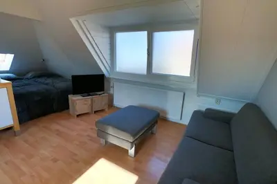 a living room with a couch and a tv at Zomerhuis At Sea op top locatie in Egmond aan zee in Egmond aan Zee