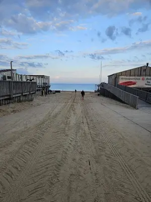a person walking on a sandy beach near the ocean at Zomerhuis At Sea op top locatie in Egmond aan zee in Egmond aan Zee