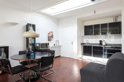 a living room with a table and chairs and a kitchen at Apartment De Drie Tulpen in Zandvoort