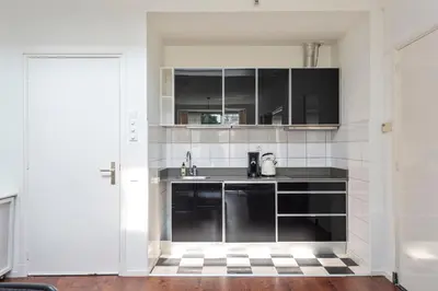 a kitchen with black cabinets and a sink at Apartment De Drie Tulpen in Zandvoort