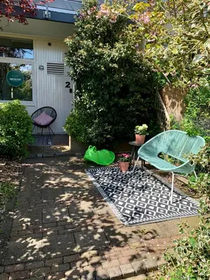 a patio with a green chair and a table at Amsterdam Beach Apartment 2, Private Garden in Zandvoort