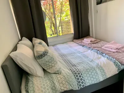 a small bedroom with a bed with a window at Amsterdam Beach Apartment 2, Private Garden in Zandvoort