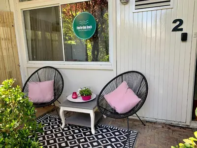two chairs and a table on a porch with pink pillows at Amsterdam Beach Apartment 2, Private Garden in Zandvoort