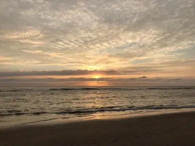 a sunset on a beach with the ocean at Beachhouse Wijk aan Zee 6 guests near beach free parking in Wijk aan Zee
