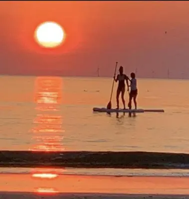 two people on a paddle board in the water at sunset at Beachhouse Wijk aan Zee 6 guests near beach free parking in Wijk aan Zee