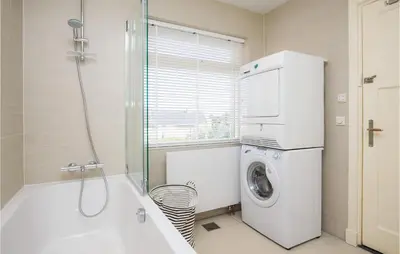 a bathroom with a tub and a washing machine at 'T Sterntje in Bergen aan Zee
