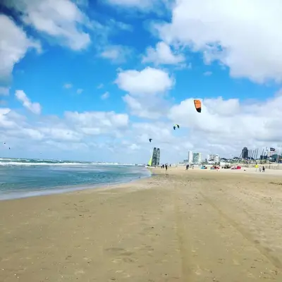 a group of people flying kites on the beach at Little Buddha in Zandvoort