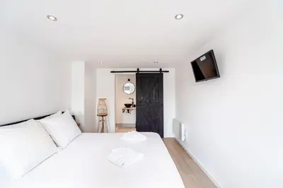 a bedroom with a white bed and a tv on a wall at Little Buddha in Zandvoort