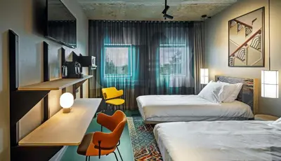 a hotel room with two beds and a table and chairs at The Florian Amsterdam Schiphol Airport, WorldHotels Crafted in Hoofddorp