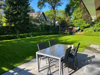 a table and chairs in a yard with a lawn at Garden find zandvoort in Bentveld