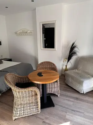 a room with a table and wicker chairs and a bed at Studio Wijkhuizen in Zandvoort