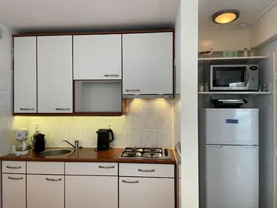 a kitchen with white cabinets and a white refrigerator at Heerlijke vakantiehuizen in Egmond in Egmond aan Zee
