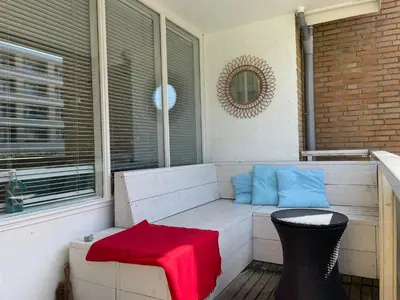 a porch with a bench with a red blanket at Heerlijke vakantiehuizen in Egmond in Egmond aan Zee