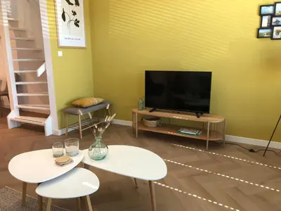 a living room with two tables and a flat screen tv at Heerlijke vakantiehuizen in Egmond in Egmond aan Zee
