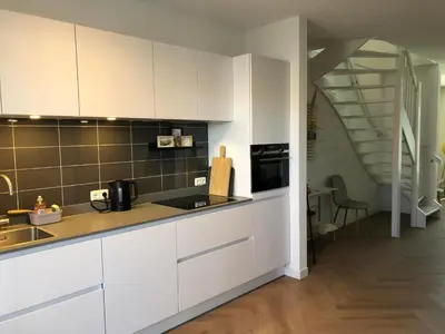 a kitchen with white cabinets and a staircase at Heerlijke vakantiehuizen in Egmond in Egmond aan Zee