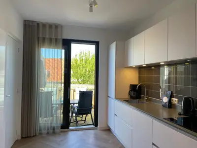 a kitchen with white cabinets and a table and a chair at Heerlijke vakantiehuizen in Egmond in Egmond aan Zee