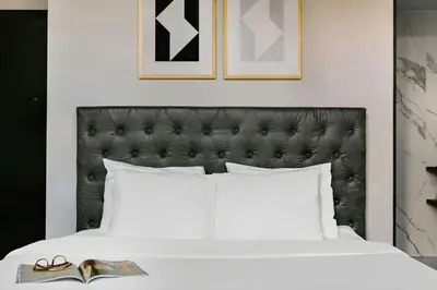 a bed with a black headboard and a book at S&A Vondel Park Hotel in Amsterdam