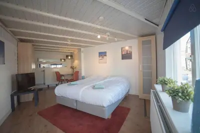 a bedroom with a bed and a desk and a television at Stop & Stay 2 in Zandvoort