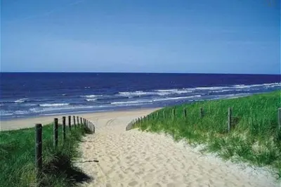 a sandy beach with a fence and the ocean at Stop & Stay 2 in Zandvoort