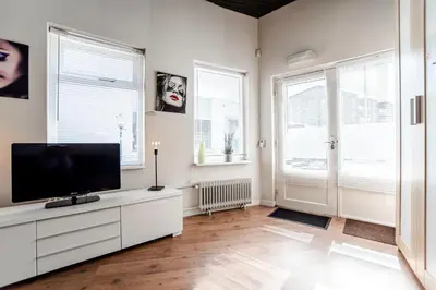 a living room with a flat screen tv and two windows at Stop & Stay 1 in Zandvoort