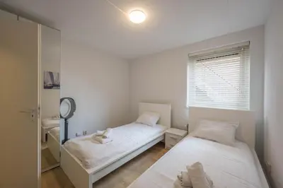 a bedroom with two beds and a mirror at Meerzicht 70 - Vakantiehuis aan het water! in Uitgeest