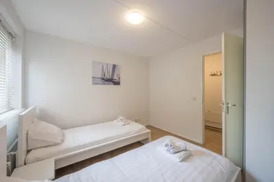 a white room with two beds and a mirror at Meerzicht 70 - Vakantiehuis aan het water! in Uitgeest