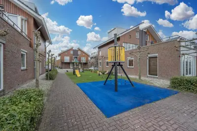 a playground in a yard with a blue carpet at Meerzicht 70 - Vakantiehuis aan het water! in Uitgeest