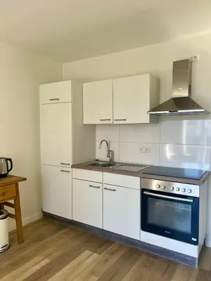 a kitchen with white cabinets and a sink and a stove at Pure Apartment in Zandvoort