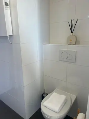 a white bathroom with a toilet with a towel on it at Pure Studio in Zandvoort