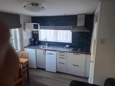 a small kitchen with white cabinets and a sink at Bakker1 in Groet