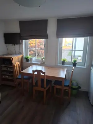 a kitchen with a wooden table and chairs and two windows at Bakker1 in Groet