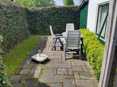 a patio with chairs and a table and a bird bath at Bakker1 in Groet
