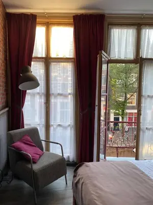 a bedroom with a bed and a chair and a window at Hotel & bar Royal taste Amsterdam in Amsterdam