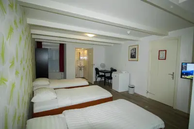a room with three beds and a table and a desk at Hotel & bar Royal taste Amsterdam in Amsterdam