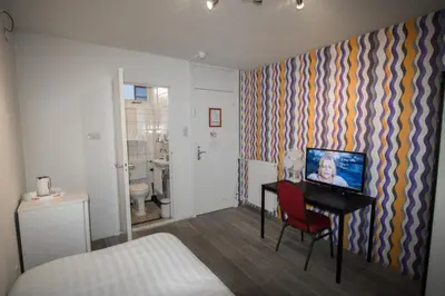 a room with a bed and a desk with a television at Hotel & bar Royal taste Amsterdam in Amsterdam