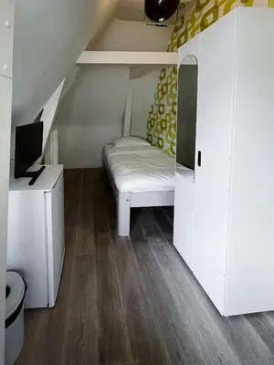 a small room with a bed and a tv in it at Hotel & bar Royal taste Amsterdam in Amsterdam
