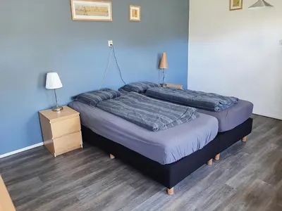 a bedroom with two beds and a night stand with a lamp at Bakker2 in Groet