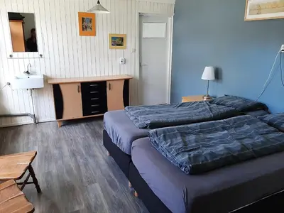 a bedroom with two beds and a table and a desk at Bakker2 in Groet
