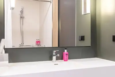 a bathroom sink with a pink soap bottle on it at Moxy Utrecht in Utrecht