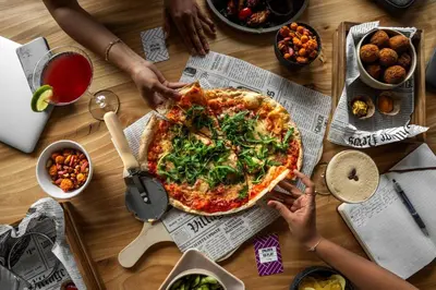 a group of people sitting around a table with a pizza at Moxy Utrecht in Utrecht