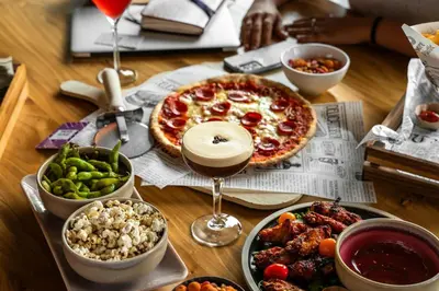 a table topped with a pizza and bowls of food at Moxy Utrecht in Utrecht