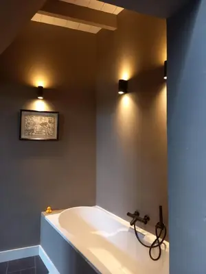 a bathroom with a tub with two lights on the wall at Vakantiehuis De Oude Bakkerij in Katwijk aan Zee