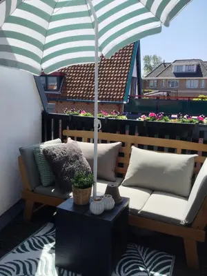 a patio with a couch and an umbrella on a balcony at Vakantiehuis De Oude Bakkerij in Katwijk aan Zee