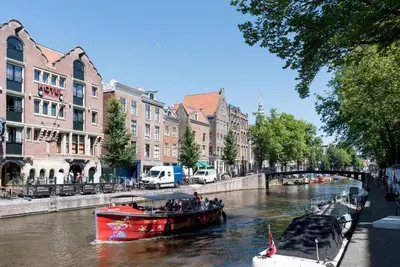 a red boat on a river in a city at RedLight District Private Smokers Friendly Studio in Amsterdam
