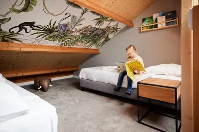 a young child sitting on a bed with a laptop at Dutchen Erfgoedpark De Hoop Appartementen in Uitgeest